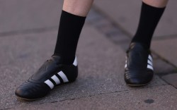 A fashion week guest is seen wearing black socks and Taekwondo Adidas sneakers