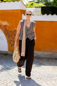 COPENHAGEN, DENMARK - AUGUST 07: Hollie Mercedes Peters wears grey sleeveless cardigan, brown pants, beige Bottega Veneta bag, scarf outside Skall Studio during day three of the Copenhagen Fashion Week (CPHFW) SS25 on August 07, 2024 in Copenhagen, Denmark. (Photo by Christian Vierig/Getty Images)