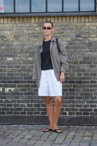 COPENHAGEN, DENMARK - AUGUST 7: A guest wears dark sunglasses, black shirt, black and dark gray pattern unbuttoned long sleeve shirt, white shorts, black flip flops, outside Herskind, during the Copenhagen Fashion Week Spring/Summer 2024-2025 on August 7, 2024 in Copenhagen, Denmark. (Photo by Edward Berthelot/Getty Images)