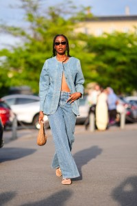 COPENHAGEN, DENMARK - AUGUST 7: A guest wears black sunglasses, gold earrings, washed light blue denim jean tailored blazer jacket, washed light blue denim jean pants, gild rings, light brown Miu Miu leather bag, white sheer mesh sandals, outside Baum und Pferdgarten, during the Copenhagen Fashion Week Spring/Summer 2024-2025 on August 7, 2024 in Copenhagen, Denmark. (Photo by Edward Berthelot/Getty Images)