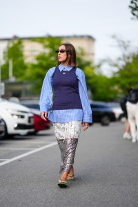 COPENHAGEN, DENMARK - AUGUST 7: Ginevra Mavilla wears black sunglasses, gold earrings, light blue white striped button up long sleeve, dark blue tank top, white and red lined pattern silver sheer mesh sequin midi skirt, white rings, green flip flops, outside Baum und Pferdgarten, during the Copenhagen Fashion Week Spring/Summer 2024-2025 on August 7, 2024 in Copenhagen, Denmark. (Photo by Edward Berthelot/Getty Images)