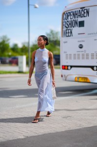 COPENHAGEN, DENMARK - AUGUST 8: A guest wears silver earrings, light blue sheer mesh midi dress, silver bracelets, silver rings, white Christian Dior small tote bag, black flip flop leather shoes, outside Munthe, during the Copenhagen Fashion Week Spring/Summer 2024-2025 on August 8, 2024 in Copenhagen, Denmark. (Photo by Edward Berthelot/Getty Images)