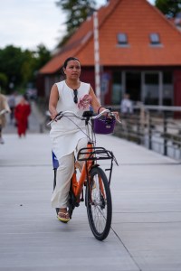 COPENHAGEN, DENMARK - AUGUST 8: A guest wears white sleeveless midi dress with pink floral detail, black sunglasses, cream pants, dark purple bag, cream flip flop, outside Marimekko, during the Copenhagen Fashion Week Spring/Summer 2024-2025 on August 8, 2024 in Copenhagen, Denmark. (Photo by Edward Berthelot/Getty Images)