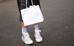 Woman holding white bag wearing sneakers